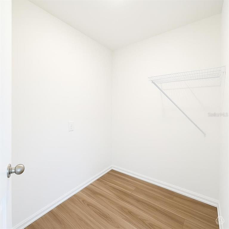 A small walk-in closet features white walls, light wood-look flooring, and a wire shelf — 13013 RED DEER PLACE, PARRISH, FL