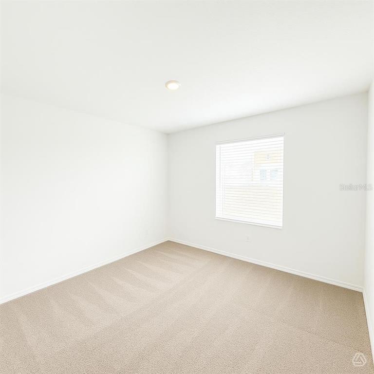 An empty bedroom features white walls, beige carpeting, and a single window with blinds — 13013 RED DEER PLACE, PARRISH, FL