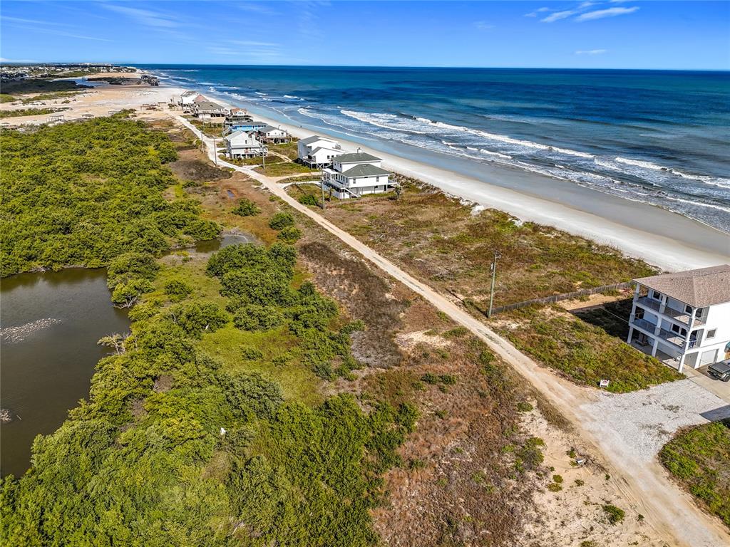 An aerial view shows a coastal landscape with houses along a beach and wetlands — 9407 OLD A1A, ST AUGUSTINE BEACH, FL
