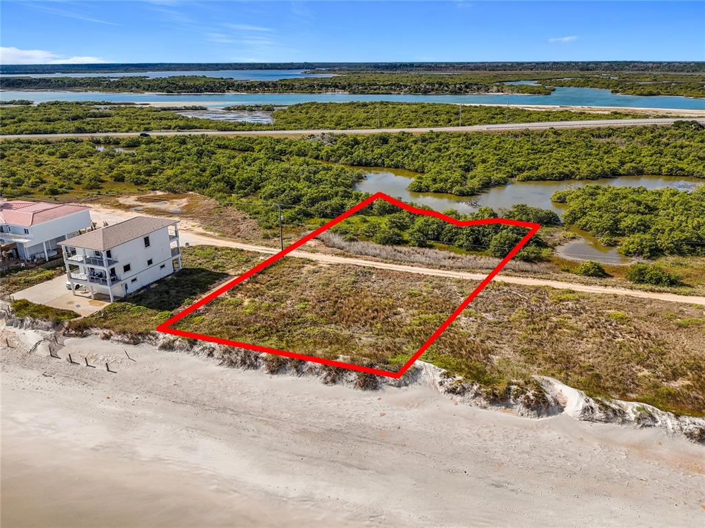 An aerial view shows a vacant, rectangular beachfront lot outlined in red next to a house — 9407 OLD A1A, ST AUGUSTINE BEACH, FL