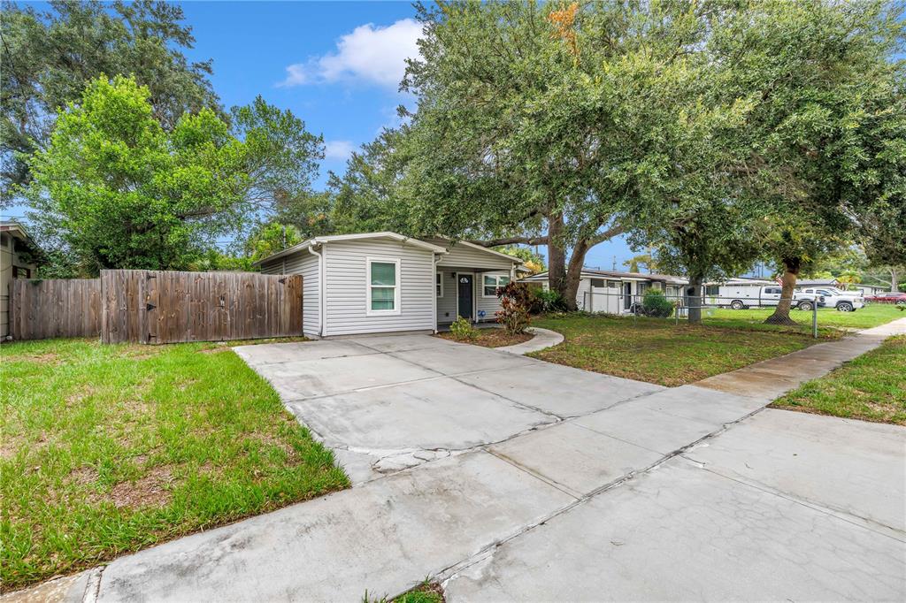 A single-story house with light gray siding, a concrete driveway, and a wooden fence — 4411 W LEILA AVENUE, TAMPA, FL