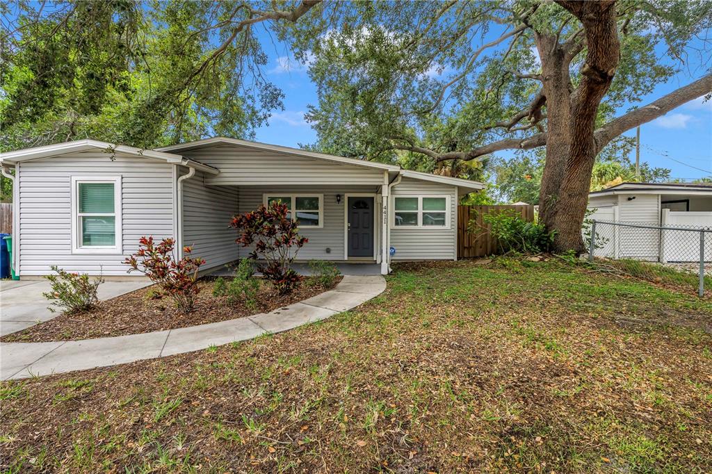 A single-story house with light gray siding, a covered entryway, and a large oak tree — 4411 W LEILA AVENUE, TAMPA, FL