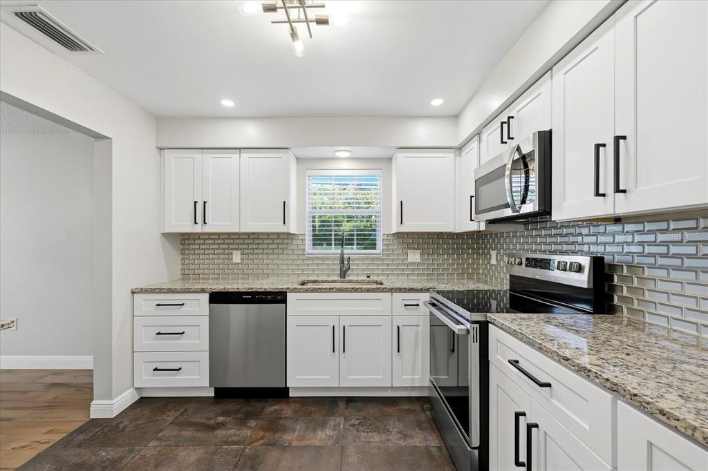 A three-story, light blue apartment building features a central arched entryway and a parking lot — 1706 BELLEAIR FOREST DRIVE UNIT 128, BELLEAIR, FL
