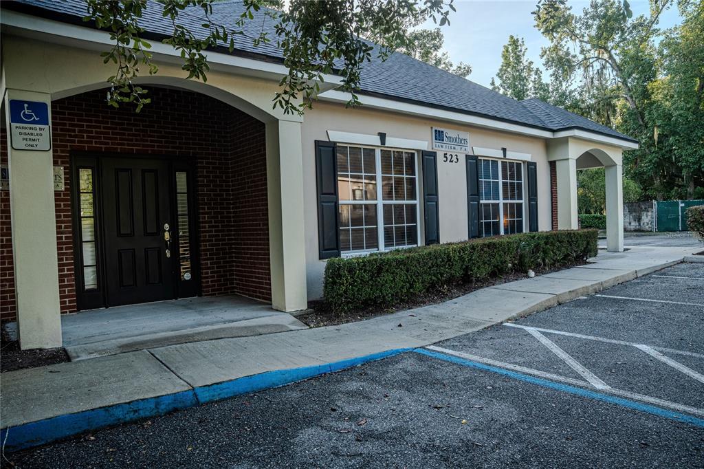 The exterior of a single-story commercial building features a brick entrance, tan stucco, and windows — 523 WEKIVA COMMONS CIRCLE UNIT 4, APOPKA, FL