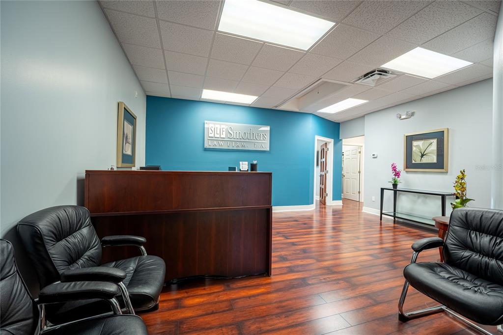 A law firm reception area features a dark wood desk, black leather chairs, and teal walls — 523 WEKIVA COMMONS CIRCLE UNIT 4, APOPKA, FL