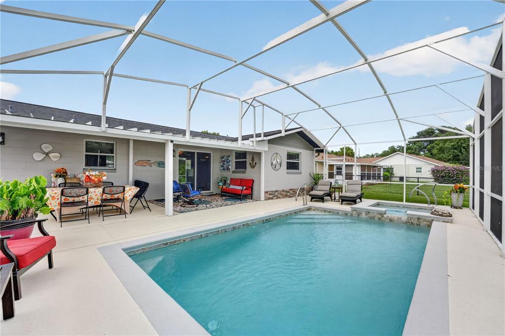 A screened-in patio features a swimming pool, a hot tub, and outdoor dining furniture — 28050 LOIS DRIVE, TAVARES, FL