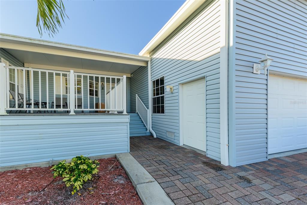 A light blue house exterior features a covered porch, a paved walkway, and a garage — 2 EMDEN CIRCLE, PUNTA GORDA, FL