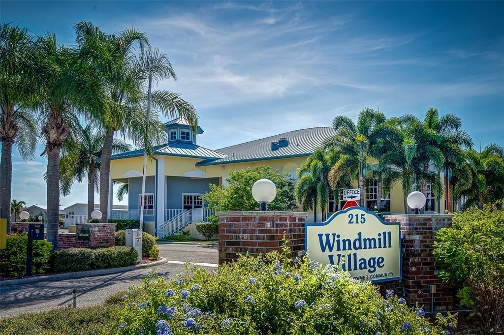 The exterior of the Windmill Village community entrance features a brick sign and palm trees — 2 EMDEN CIRCLE, PUNTA GORDA, FL