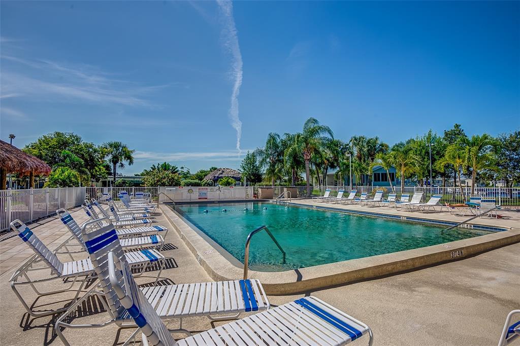 A swimming pool surrounded by lounge chairs, palm trees, and a white fence — 2 EMDEN CIRCLE, PUNTA GORDA, FL