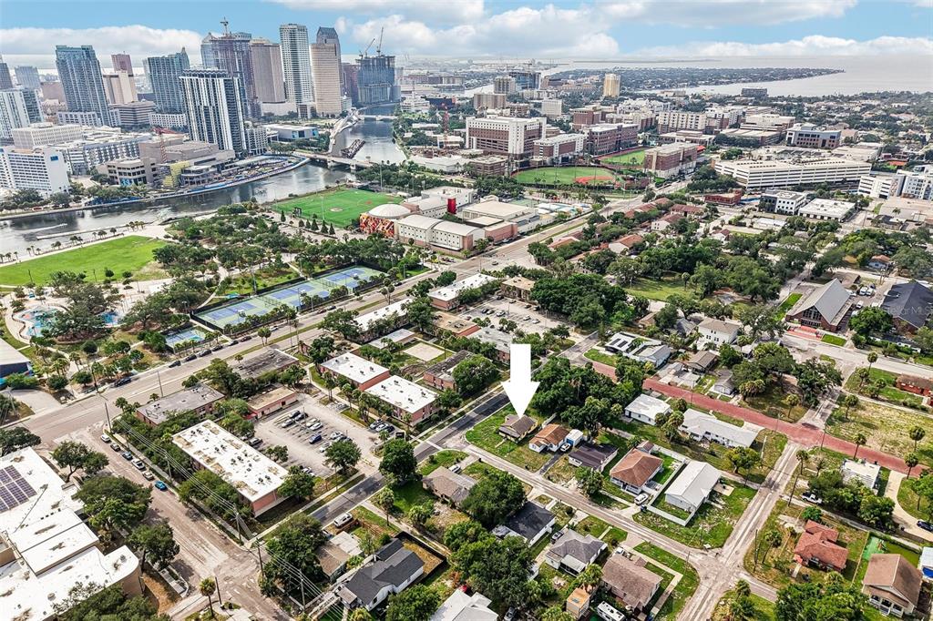 An aerial view shows a residential neighborhood with a white arrow pointing to a house — 1002 W NASSAU STREET, TAMPA, FL