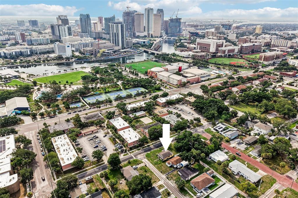 An aerial view shows a residential neighborhood with a white arrow pointing to a house — 1002 W NASSAU STREET, TAMPA, FL