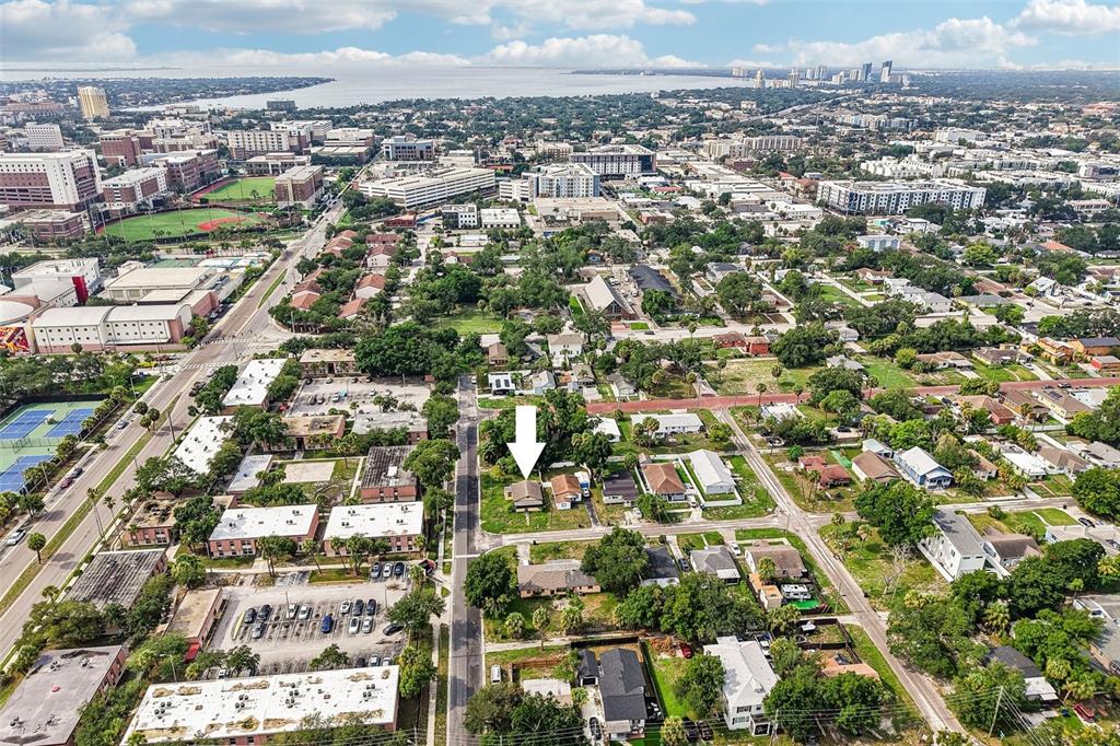 An aerial view shows a residential neighborhood with a white arrow pointing to a house — 1002 W NASSAU STREET, TAMPA, FL
