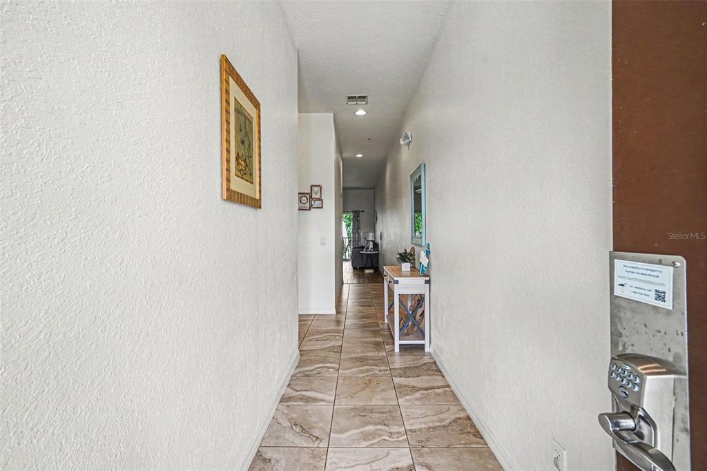 A tiled hallway leads from an entryway toward a living area with a console table — 114 LUCAYA LOOP UNIT 114, DAVENPORT, FL