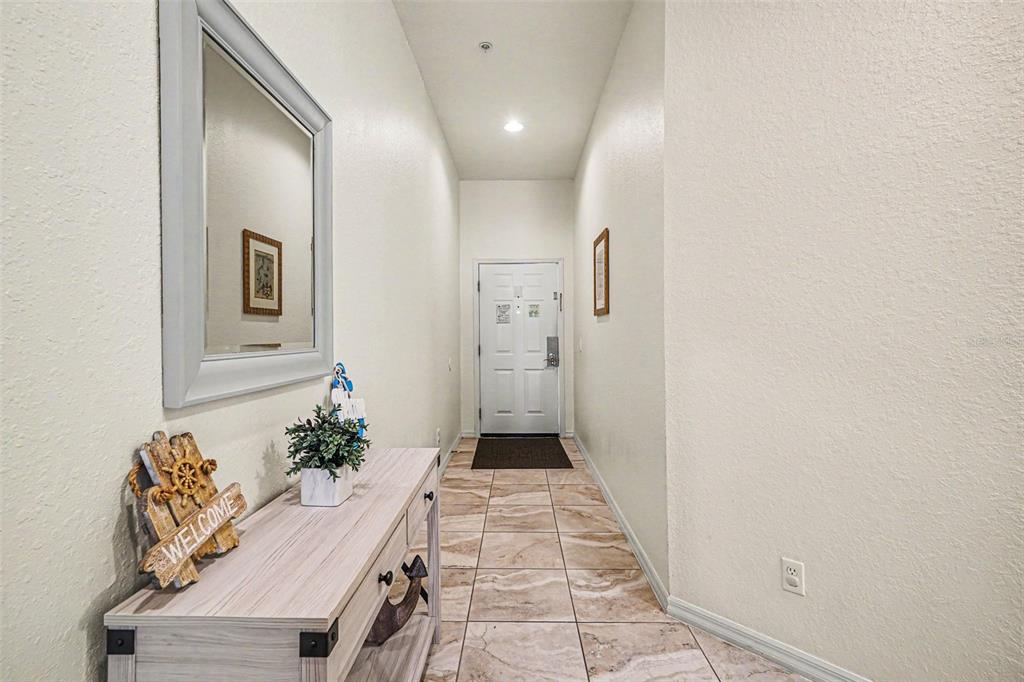 A narrow entryway features a light wood console table, a wall mirror, and tile flooring — 114 LUCAYA LOOP UNIT 114, DAVENPORT, FL