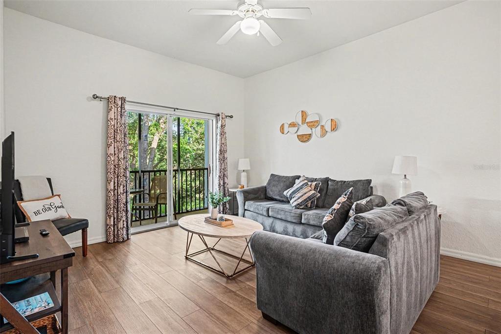 A living room features gray sofas, a wood coffee table, and a sliding glass door — 114 LUCAYA LOOP UNIT 114, DAVENPORT, FL