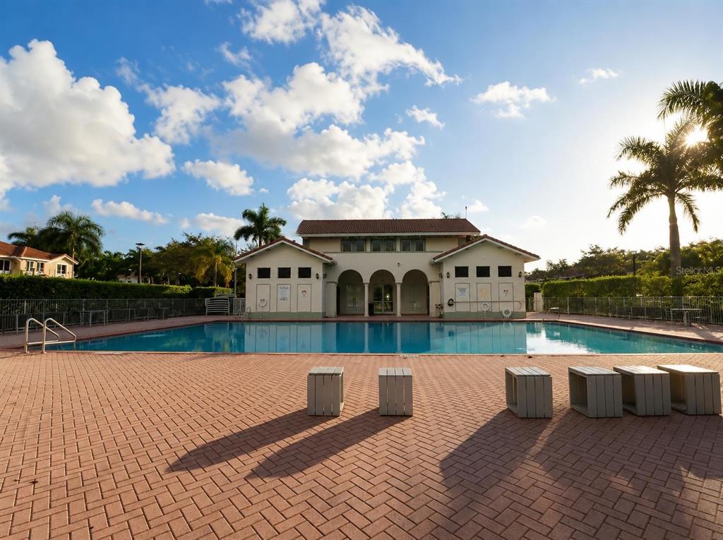 A swimming pool sits in front of a community building with a brick patio — 1452 SE 24TH AVENUE, HOMESTEAD, FL