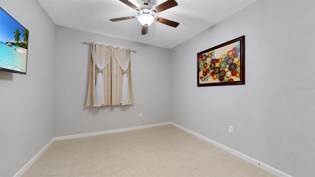 A bedroom with light gray walls, tile flooring, a ceiling fan, and a window — 1452 SE 24TH AVENUE, HOMESTEAD, FL