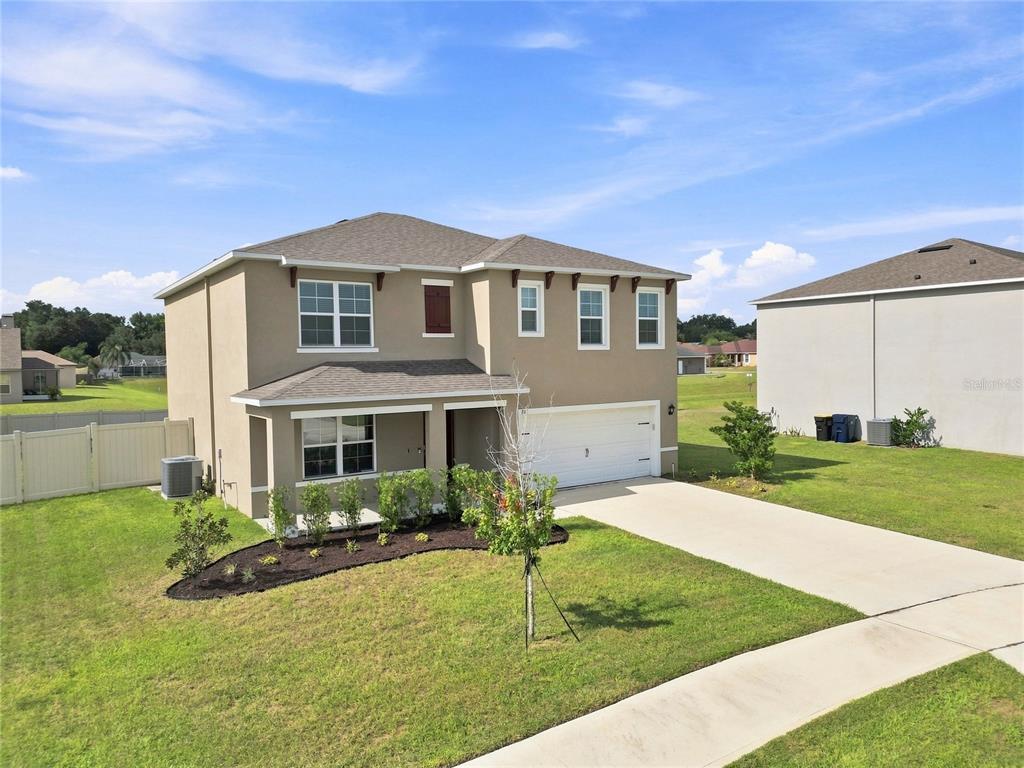 A two-story suburban house with a tan stucco exterior, a white garage, and a lawn — 787 AUBURN GROVE CT., AUBURNDALE, FL