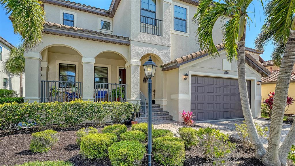 A two-story stucco house features a covered front porch, a garage, and landscaped front yard — 5723 TITLE ROW DRIVE, BRADENTON, FL