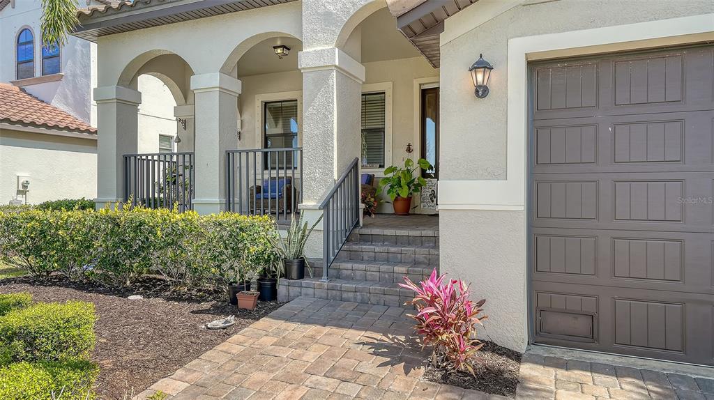 A house exterior features a paved walkway, a covered front porch, and a garage door — 5723 TITLE ROW DRIVE, BRADENTON, FL