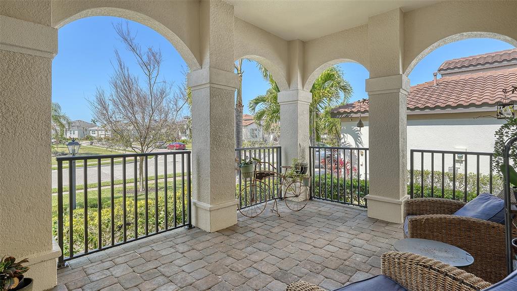 A covered patio features arched columns, a paver floor, and a black metal railing — 5723 TITLE ROW DRIVE, BRADENTON, FL