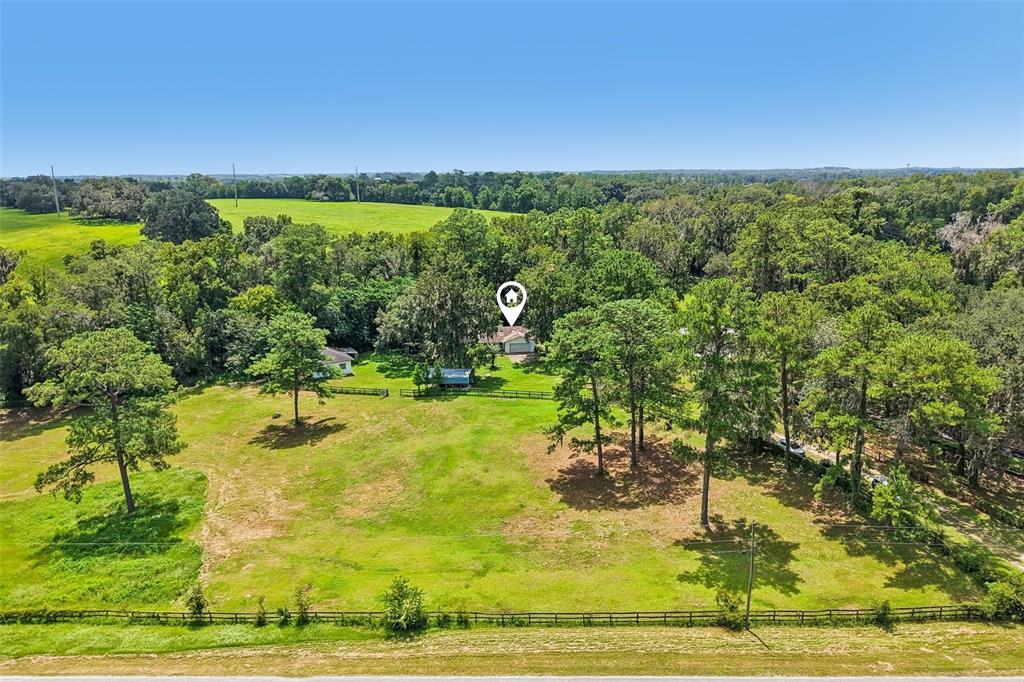 An aerial view shows a house nestled among trees on a large, grassy rural lot — 5230 NW 144TH PLACE, REDDICK, FL