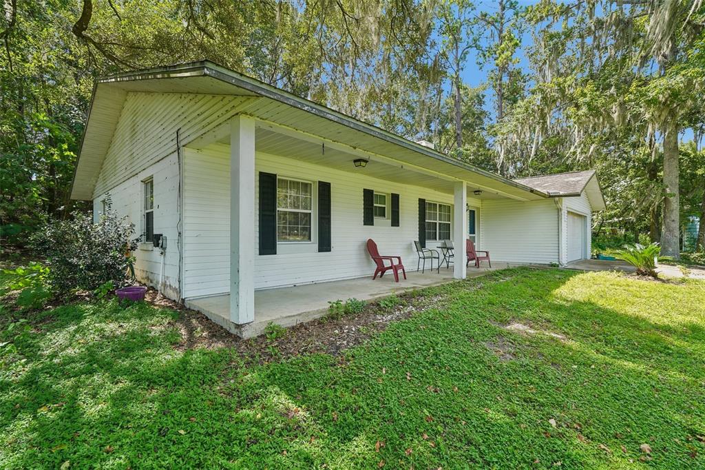 A white, single-story house with a covered front porch, black shutters, and a side garage — 5230 NW 144TH PLACE, REDDICK, FL