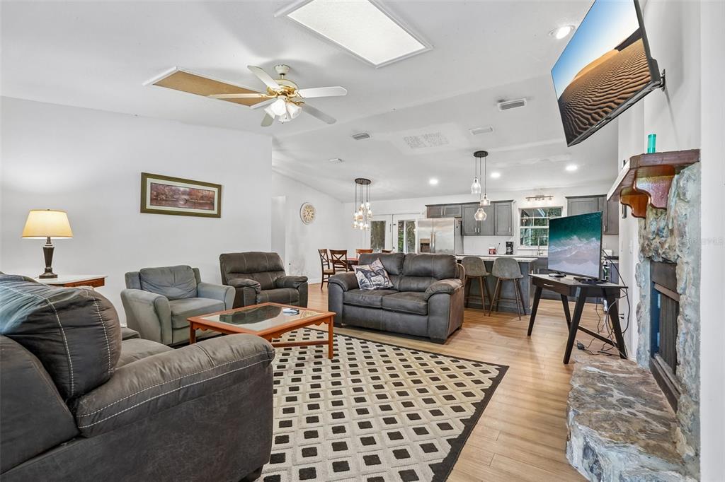 A living room features a stone fireplace, gray leather furniture, and an open kitchen area — 5230 NW 144TH PLACE, REDDICK, FL