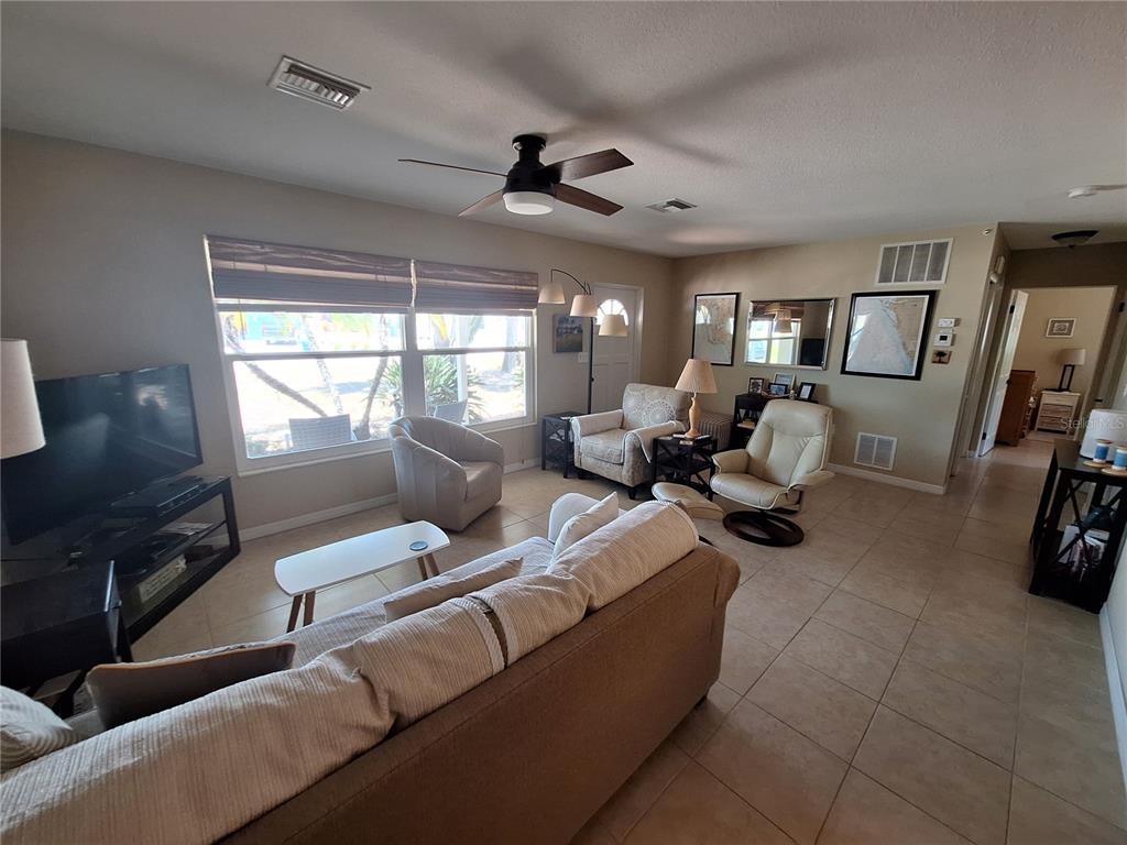 A living room features tile flooring, a ceiling fan, a sofa, and two armchairs — 1541 CREST DRIVE, ENGLEWOOD, FL