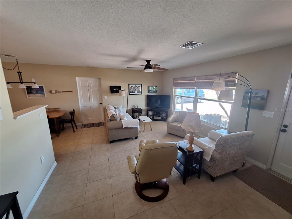 A living room with tile flooring, a ceiling fan, and a dining area — 1541 CREST DRIVE, ENGLEWOOD, FL