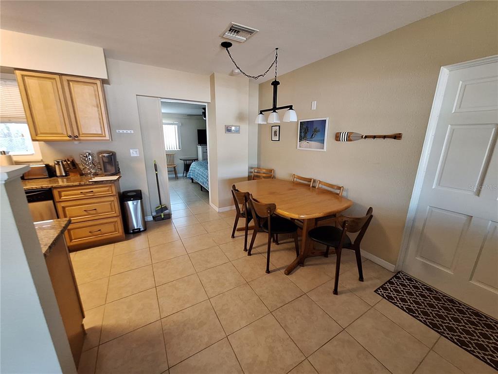 A kitchen and dining area with light wood cabinets, tile flooring, and a wooden table — 1541 CREST DRIVE, ENGLEWOOD, FL