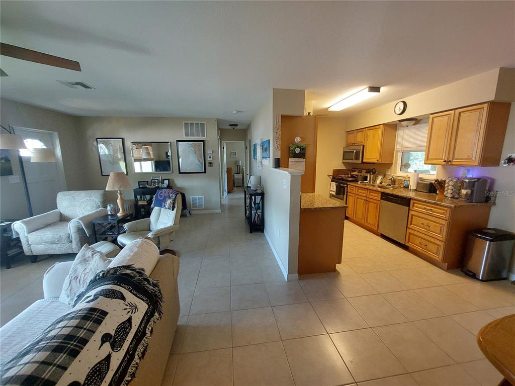An open-concept living room flows into a kitchen with wood cabinets and tile flooring — 1541 CREST DRIVE, ENGLEWOOD, FL