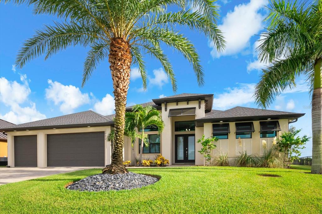 A single-story house with a three-car garage, palm trees, and a manicured lawn — 10572 RAINSVILLE STREET, PORT CHARLOTTE, FL