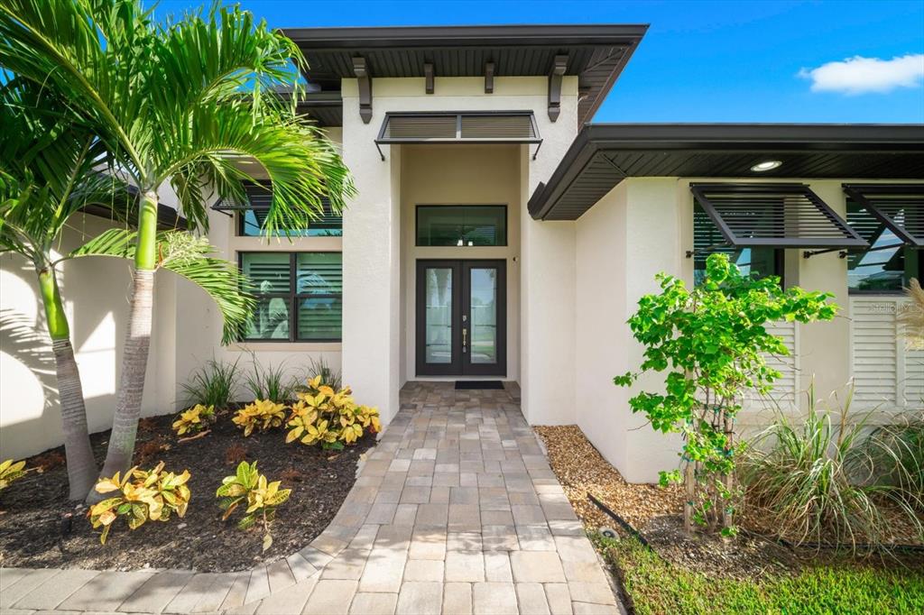 The exterior of a modern home features a paved walkway leading to a double front door — 10572 RAINSVILLE STREET, PORT CHARLOTTE, FL