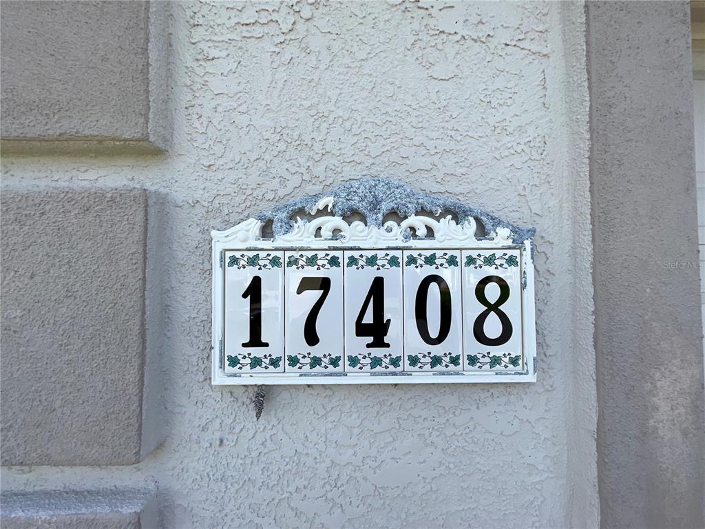 A decorative address plaque with the number 17408 is mounted on a textured stucco wall — 17408 SE 121ST CIRCLE, SUMMERFIELD, FL