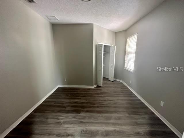 An empty bedroom features gray walls, dark wood-look flooring, and an open white closet — 11732 VIA LUCERNA CIRCLE, WINDERMERE, FL