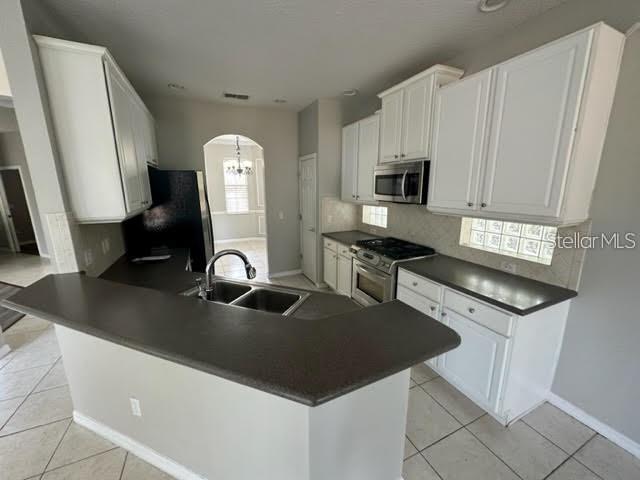 A kitchen features white cabinets, dark countertops, stainless steel appliances, and light tile flooring — 11732 VIA LUCERNA CIRCLE, WINDERMERE, FL