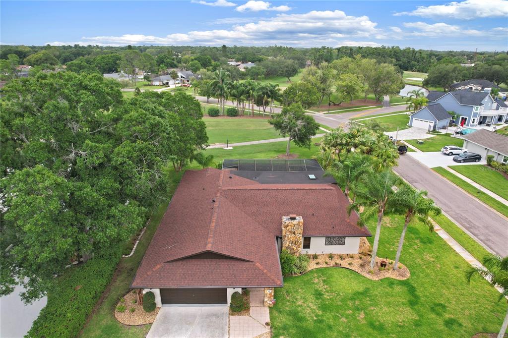 An aerial view shows a single-story house with a brown roof, stone chimney, and pool — 10 ARBOR LANE, OLDSMAR, FL