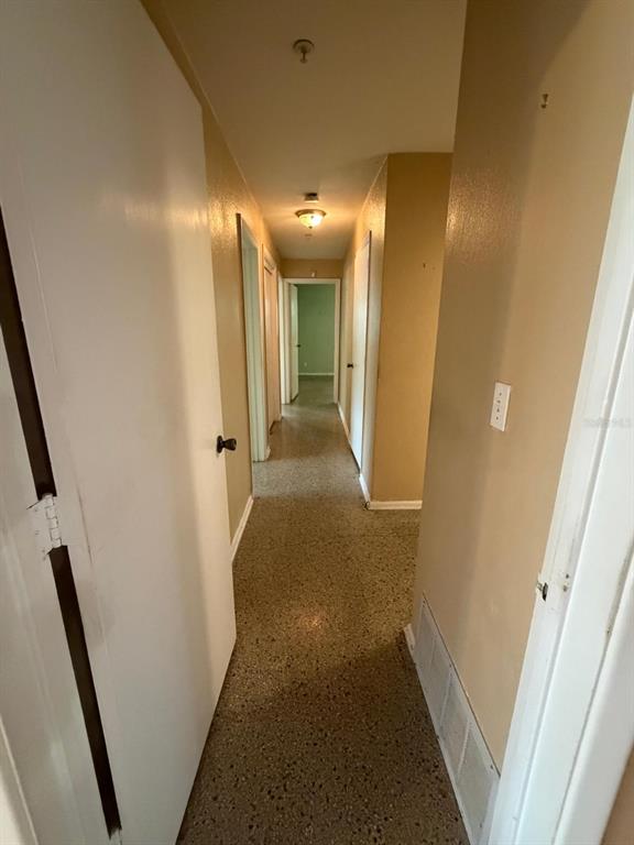 A hallway with light-colored walls, a speckled floor, and multiple closed interior doors — 8283 LE MESA STREET, ORLANDO, FL