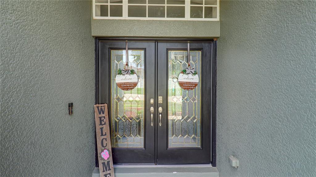 A front entryway features double black doors with glass inserts and a transom window above — 5725 JUSTICIA LOOP, LAND O LAKES, FL