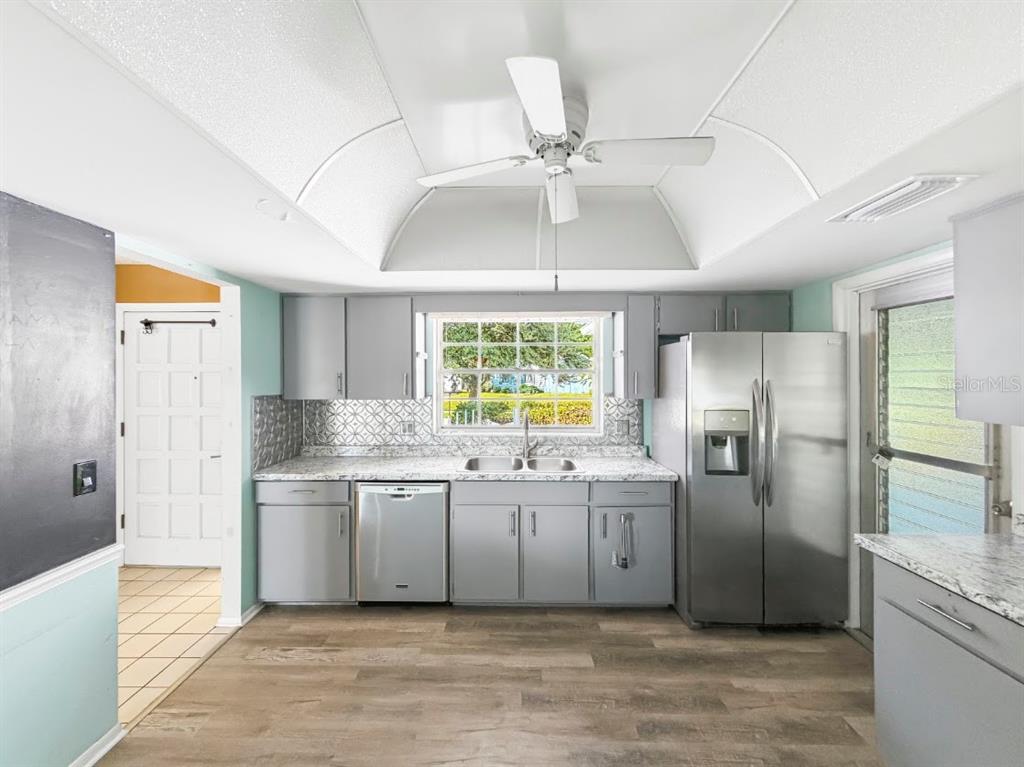 A kitchen features gray cabinets, stainless steel appliances, a patterned backsplash, and a ceiling fan — 3 HERITAGE COVE COURT, CASSELBERRY, FL