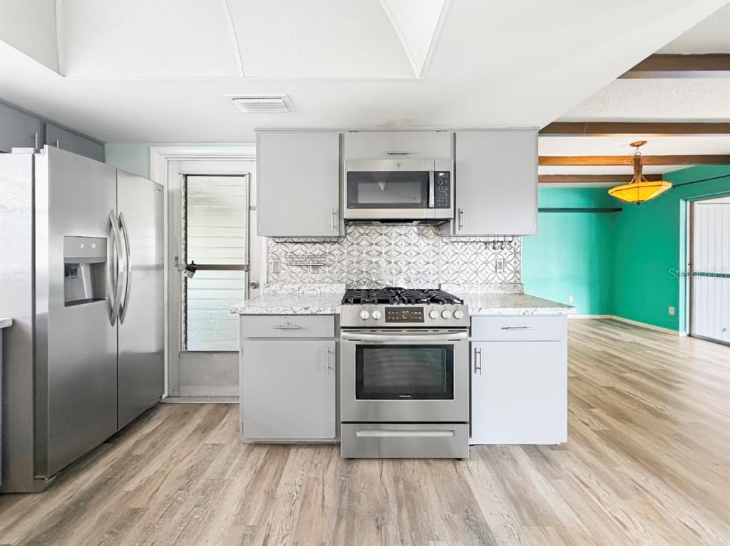 A kitchen featuring grey cabinets, stainless steel appliances, and a patterned tile backsplash — 3 HERITAGE COVE COURT, CASSELBERRY, FL
