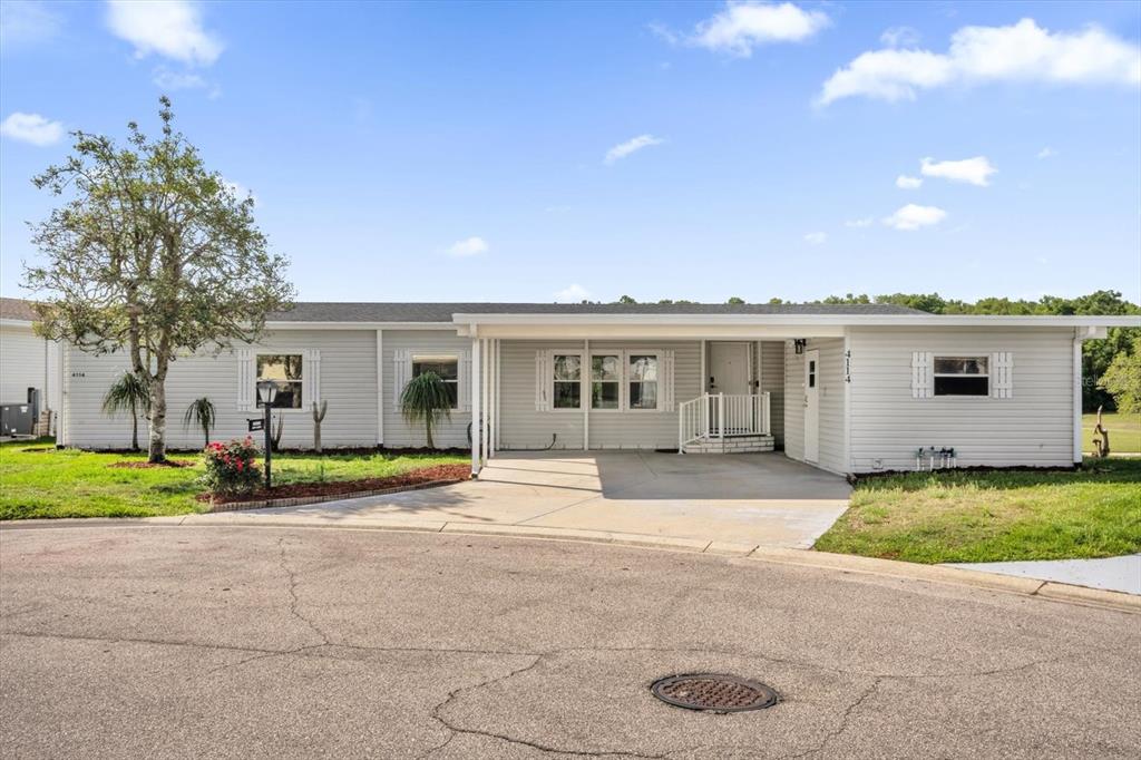 A single-story house with light gray siding features a front carport and a paved driveway — 4114 MYRTLE OAK COURT UNIT 852, ZELLWOOD, FL