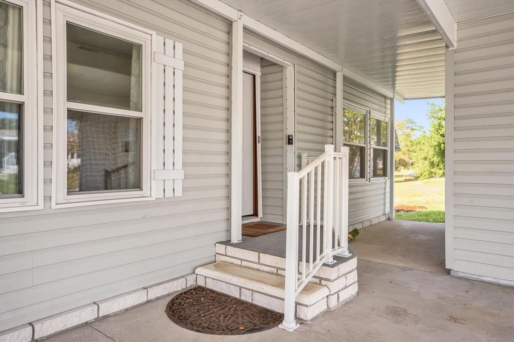A covered porch with light gray siding, a white railing, and steps leading to a door — 4114 MYRTLE OAK COURT UNIT 852, ZELLWOOD, FL