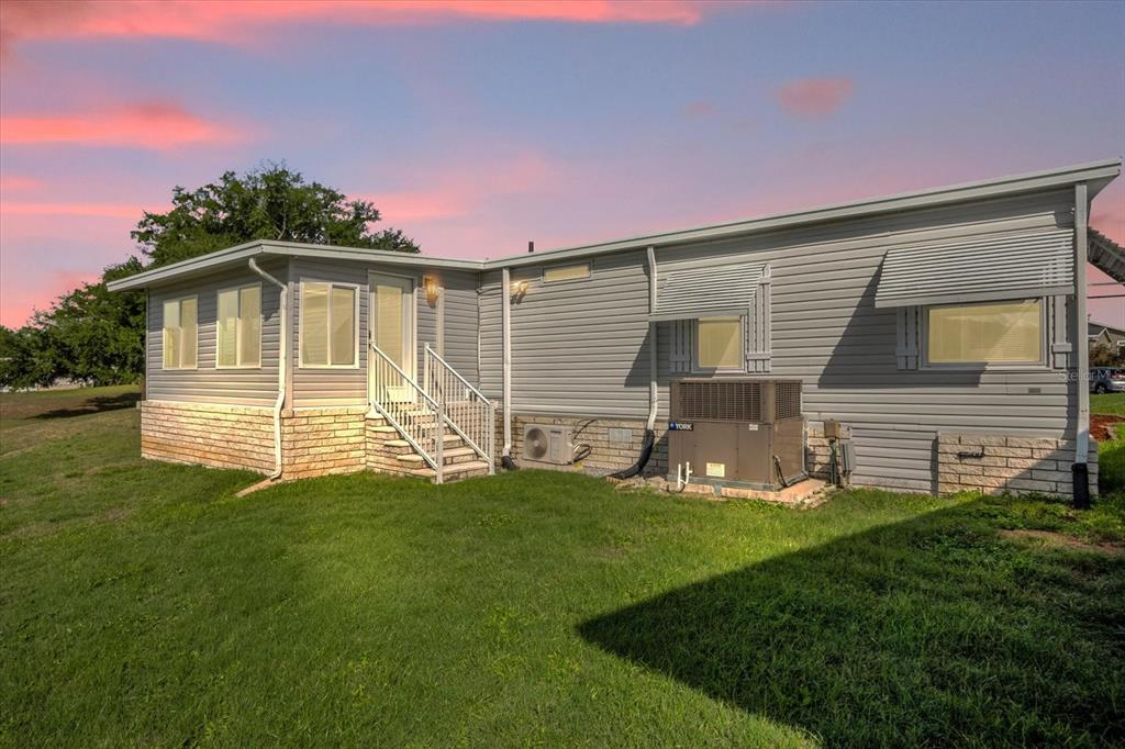 A side view of a gray manufactured home with a stone base and a central staircase — 4114 MYRTLE OAK COURT UNIT 852, ZELLWOOD, FL
