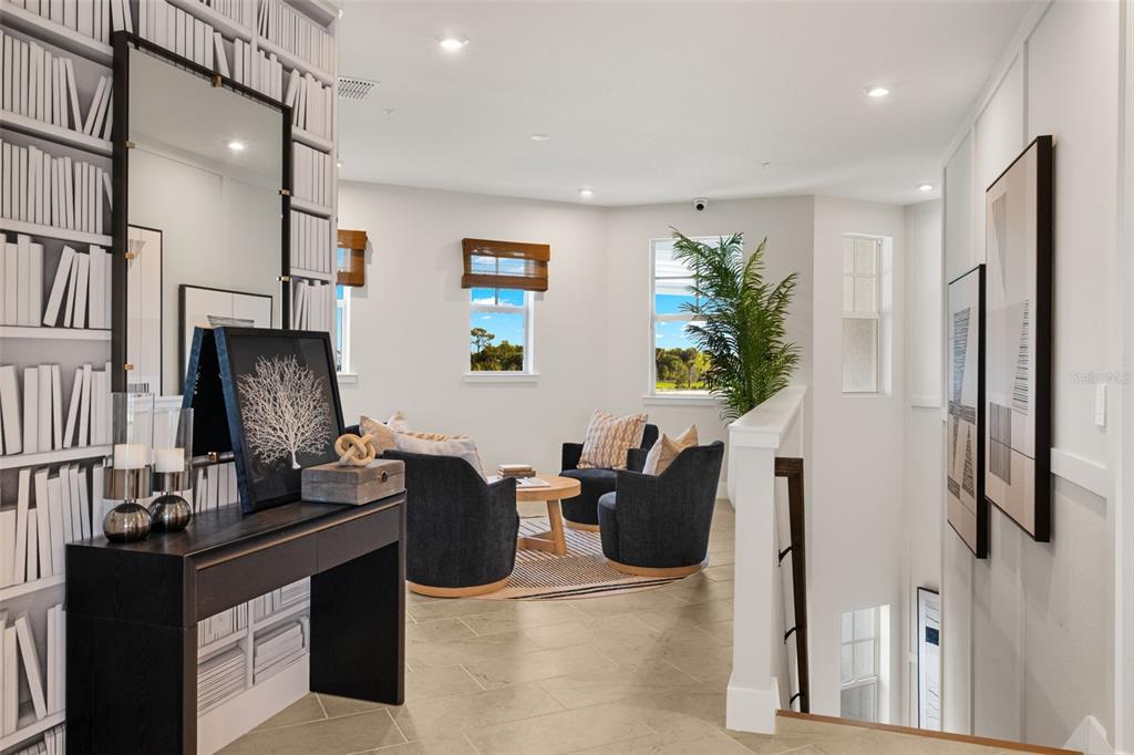 A furnished loft area features a console table, two armchairs, and a built-in bookshelf wall — 12807 JADE EMPRESS LOOP UNIT 201, VENICE, FL