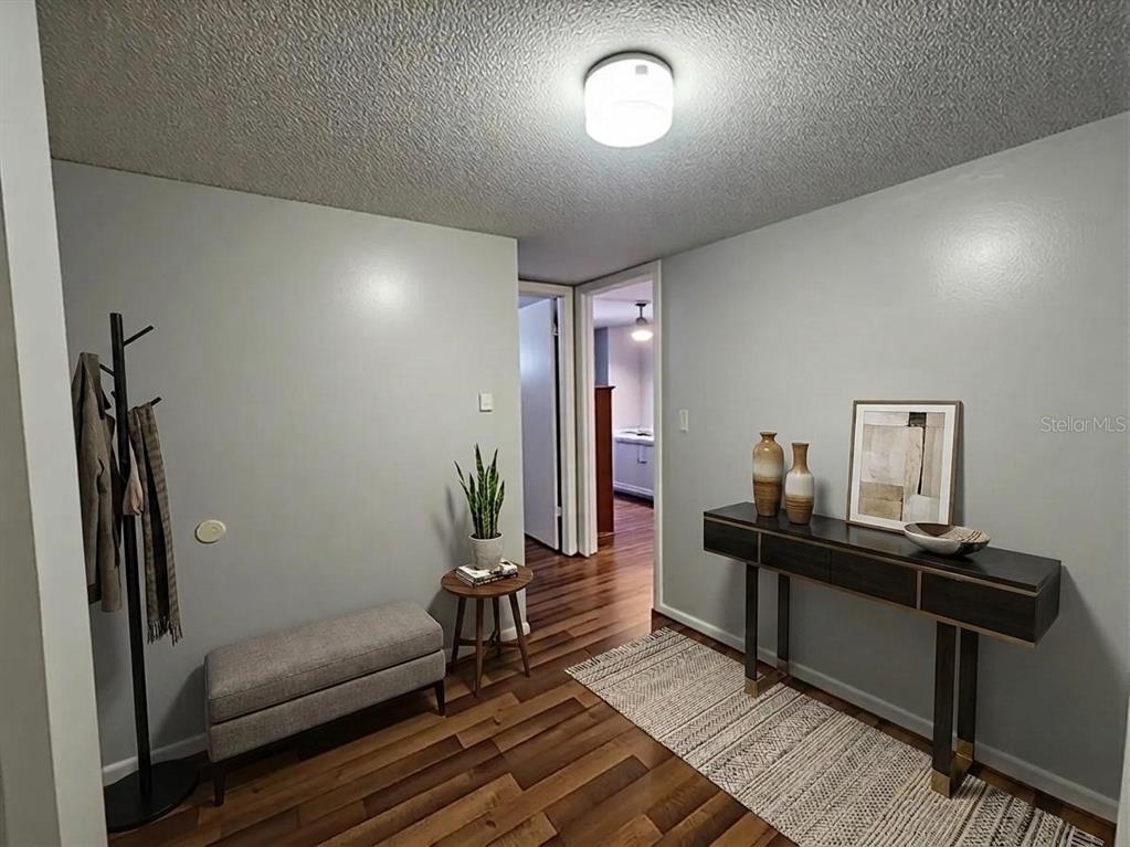 A hallway features wood flooring, a console table, a bench, and a coat rack — 626 FAIRWAYS CIRCLE UNIT A, OCALA, FL