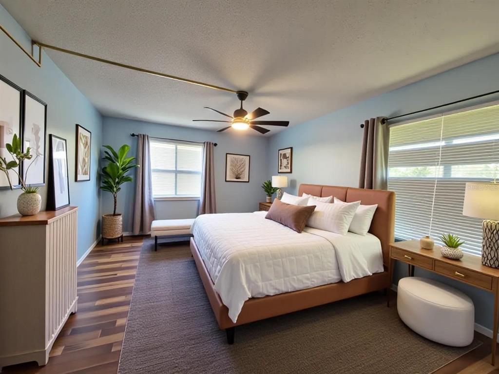 A bedroom features light blue walls, a brown upholstered bed, and wood-look flooring — 626 FAIRWAYS CIRCLE UNIT A, OCALA, FL