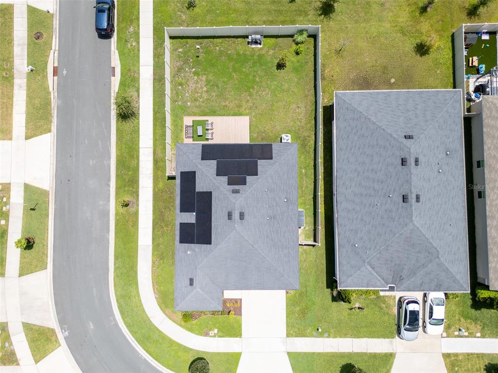 An aerial view shows a house with solar panels on the roof and a fenced yard — 3122 EAGLE HAMMOCK CIRCLE, KISSIMMEE, FL