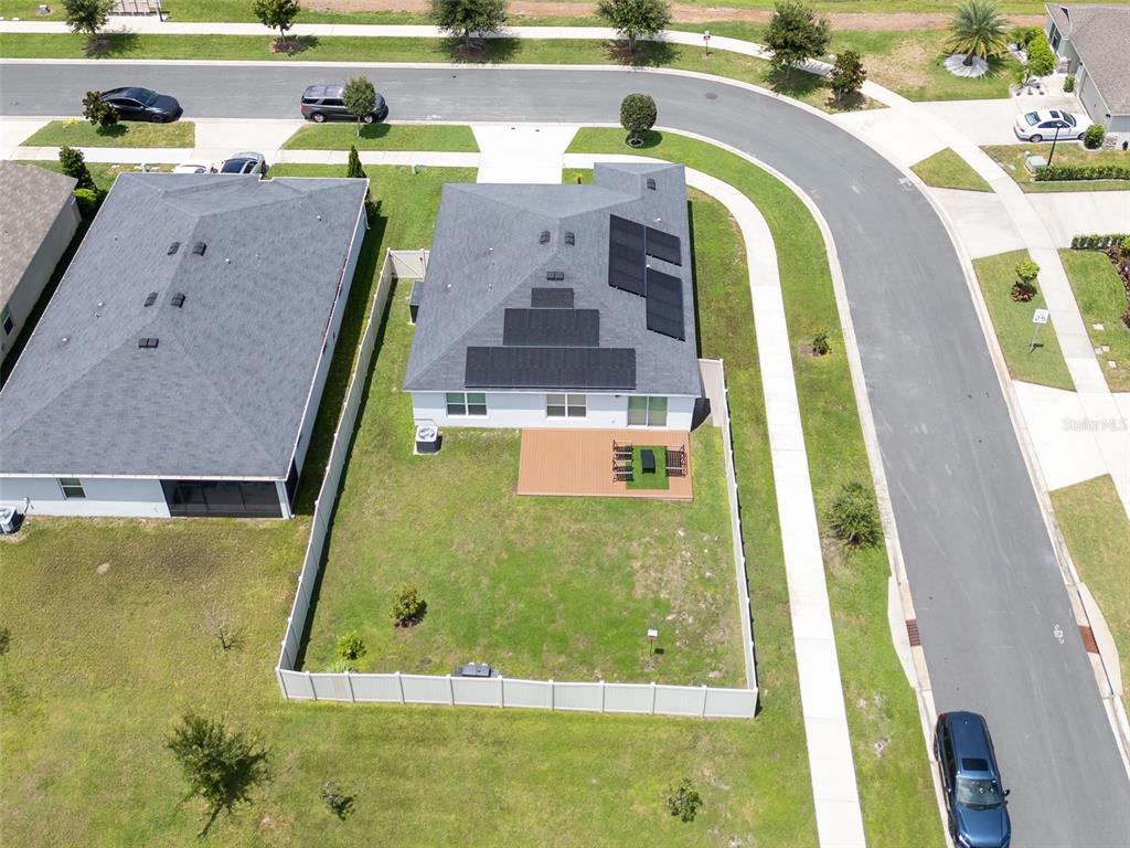 An aerial view shows a house with solar panels on the roof and a fenced backyard — 3122 EAGLE HAMMOCK CIRCLE, KISSIMMEE, FL